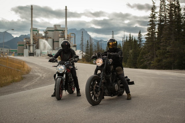 Dvaja motorkári v čiernych overaloch stoja na ceste