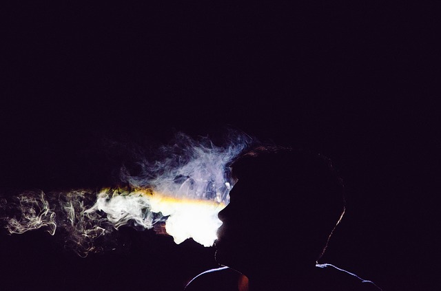 Silueta muža v tme, ktorý vyfukuje cigaretový dym.jpg