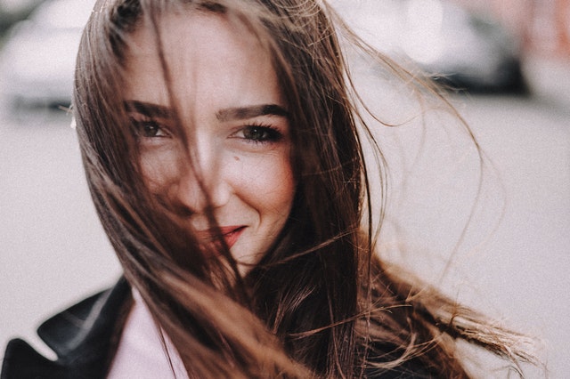 Dievča s vlasmi cez tvár sa usmieva